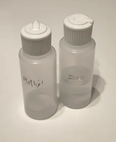 Two small plastic dispenser bottles with flip caps, hand-labelled Methyl and Iso