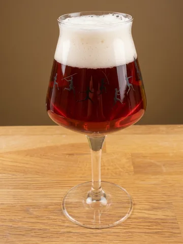 Clear, deep ruby-red beer in a stemmed tulip glass decorated with black running figures, with a thick white head